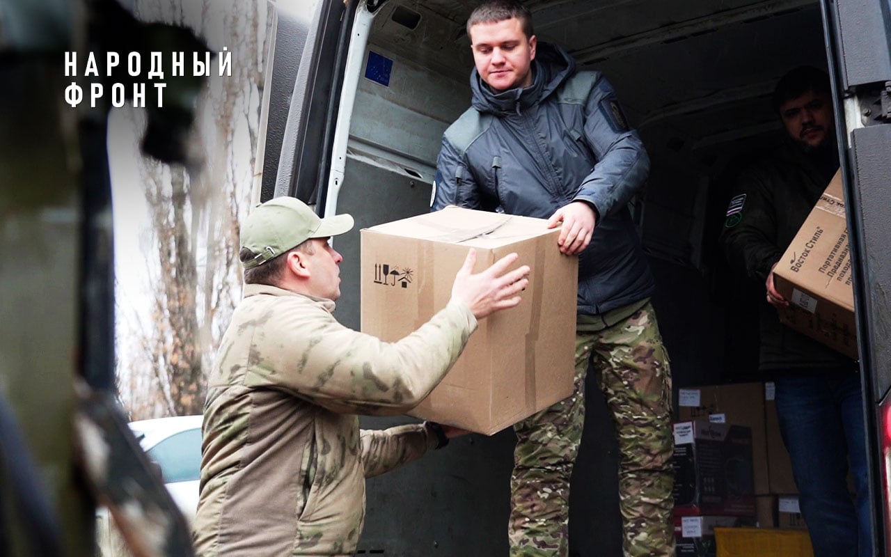 Волонтёры передают коробку с гуманитарной помощью из фургона